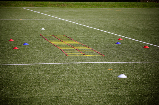 Agility ladder and marker cones set up on a turf field for speed drills