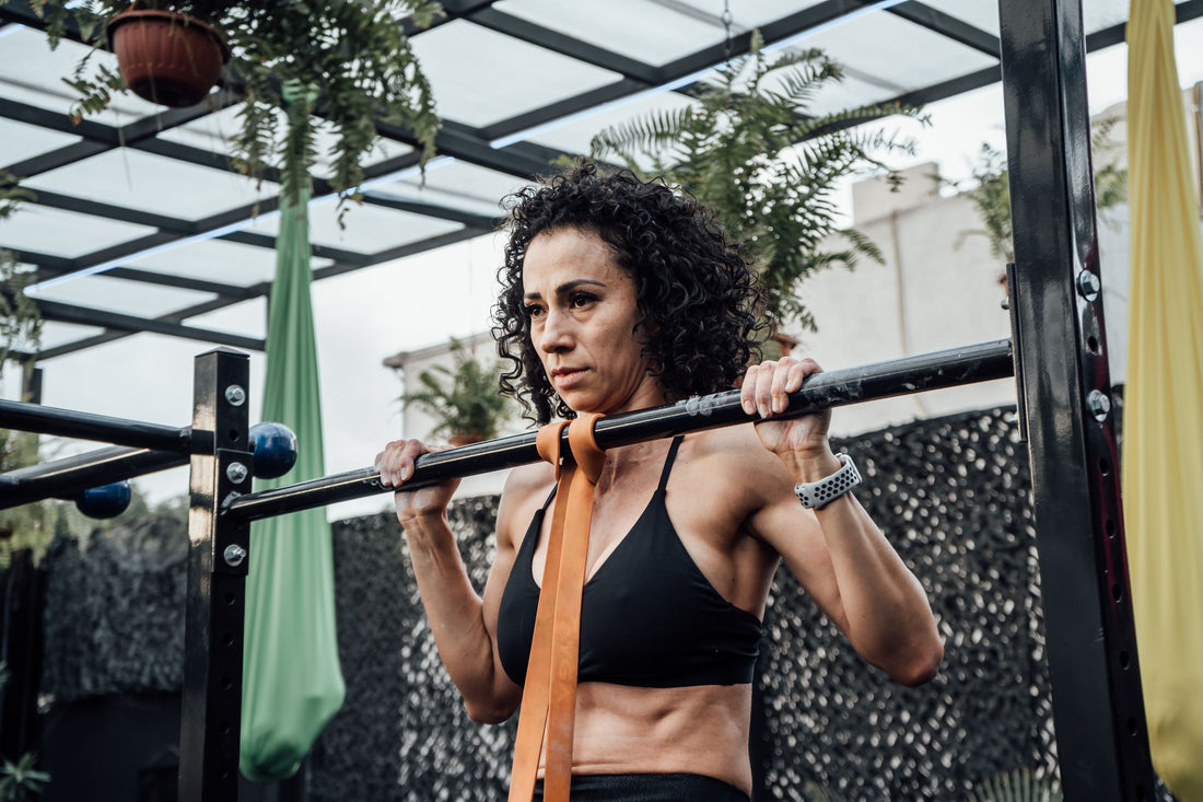 Person practicing a band-assisted pull-up on an outdoor training bar