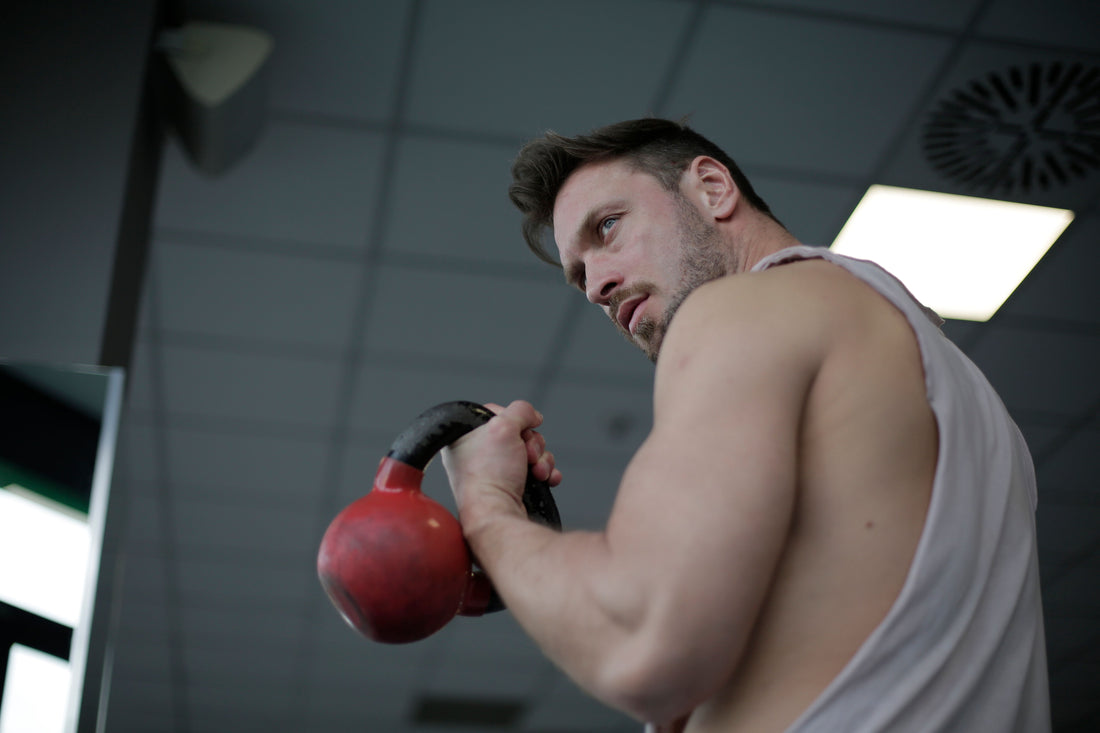 Man performing a kettlebell swing during a gym workout
