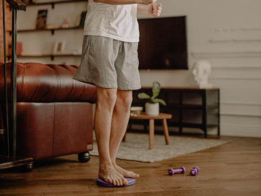 Adult practicing a controlled standing balance and rotation drill on a twist board at home