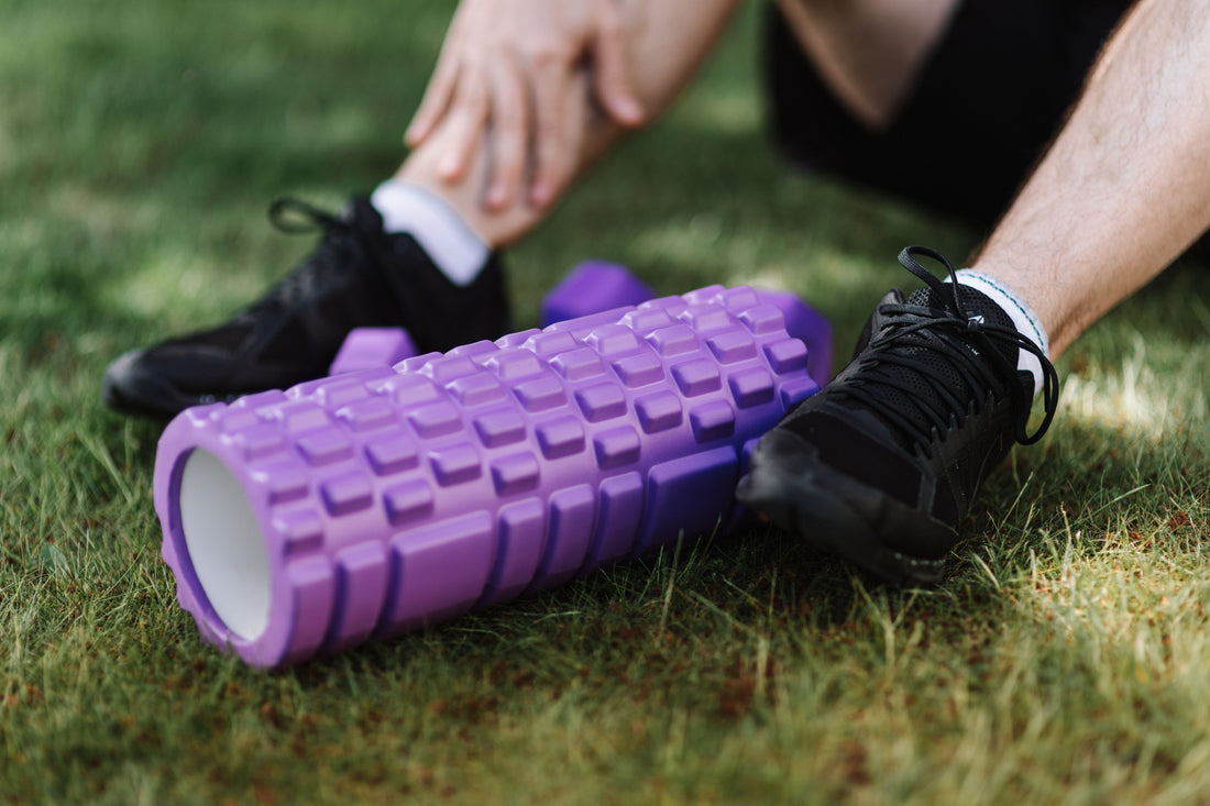 Foam roller and sneakers on grass for post-workout recovery